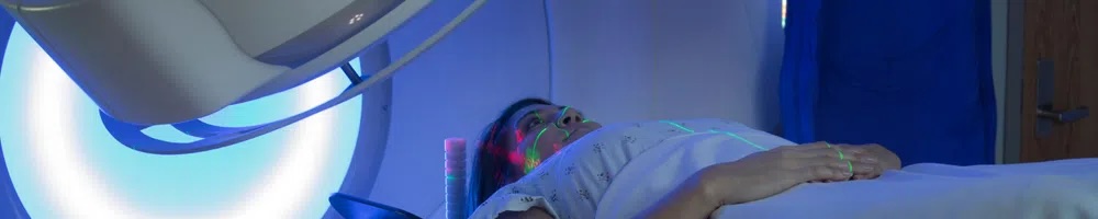 A woman lays on a CT scan bed during a procedure.