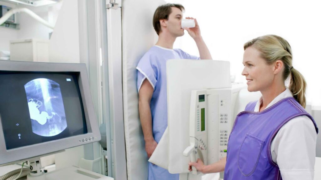 A radiologic technologist takes an X-ray during an oral contrast procedure.
