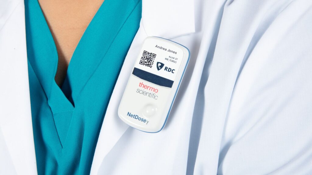 A doctor wears NetDose, a digital dosimeter, on her white coat.