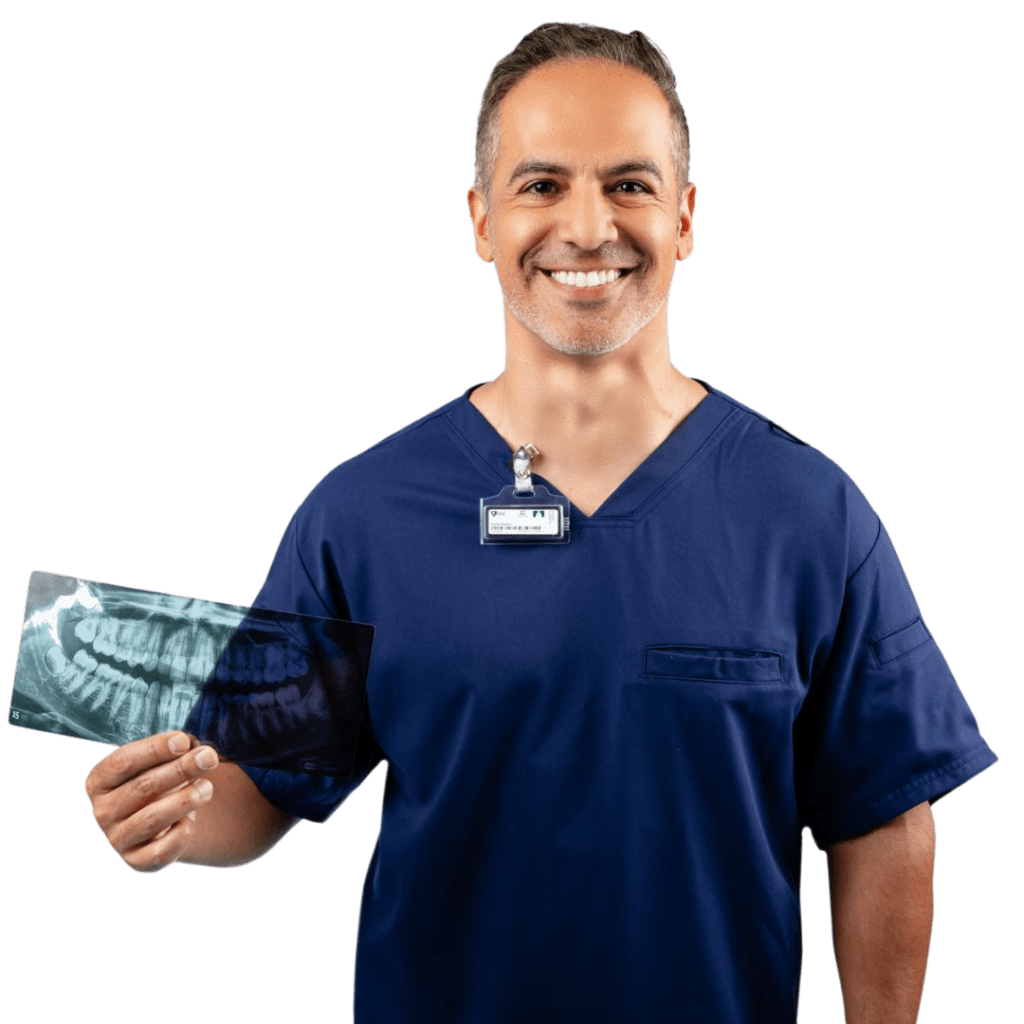 A dentist smiling and holding an X-ray while wearing a dosimeter badge.