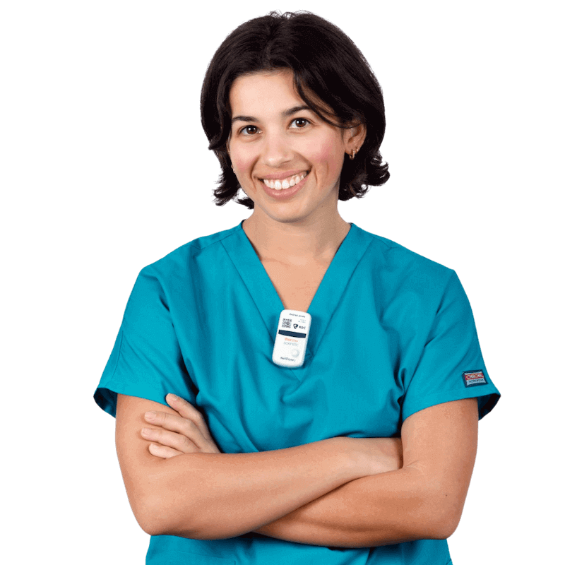 A healthcare worker wears a digital dosimeter clipped to her scrubs.