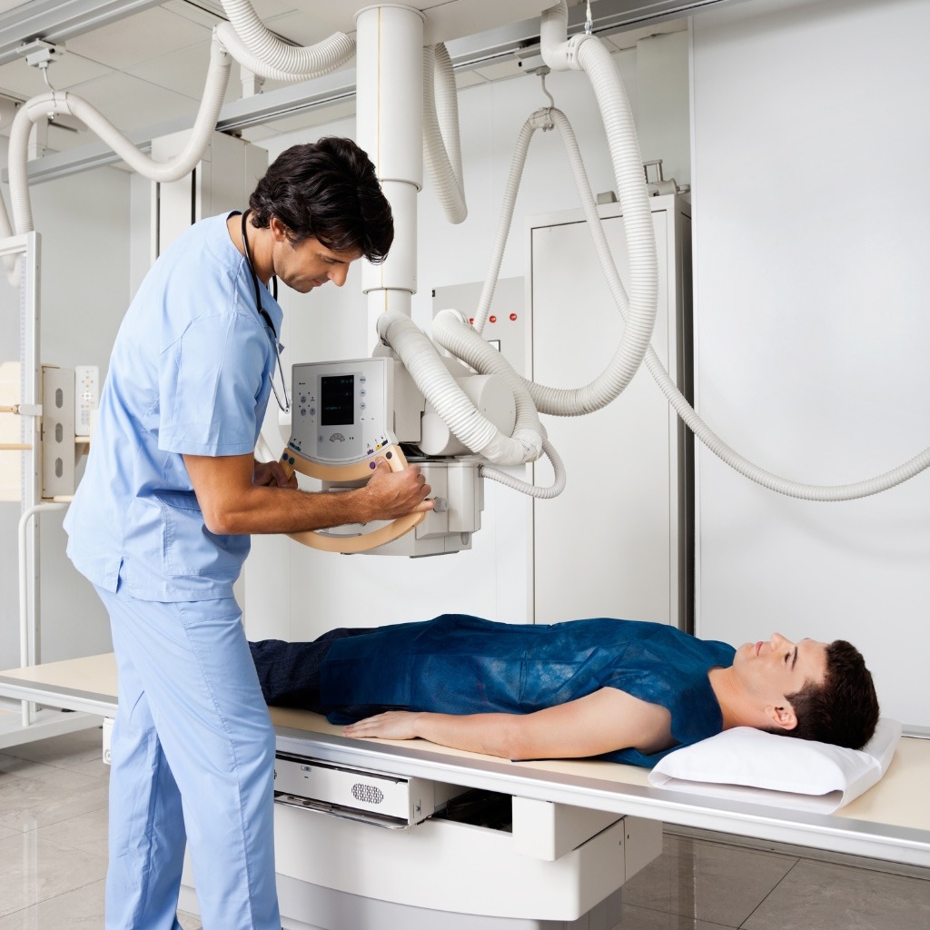 A healthcare worker positions imaging equipment for a patient.