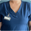 Whole Body OSL Dosimeter clipped to the collar of a vet tech's scrubs against a dark blue background.