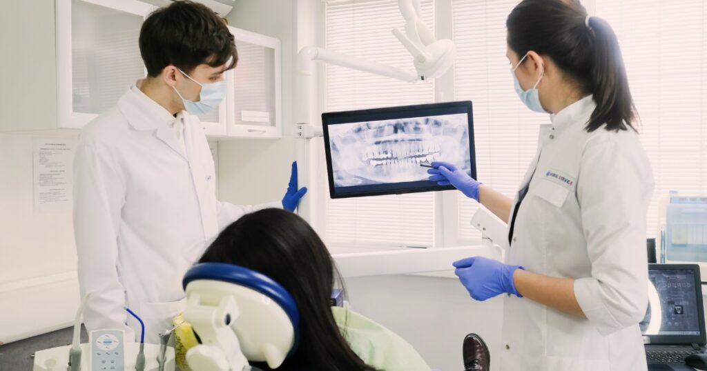 A dentist and dental technician review x-rays with a client.