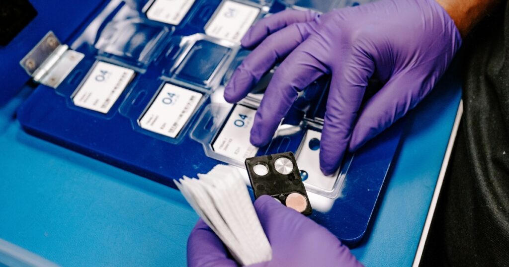 An employee at Radiation Detection Company puts together the components of a TLD badge order.