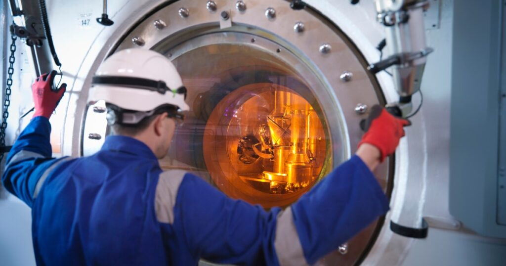 An engineer uses a fuel rod handling machine at a nuclear energy station.