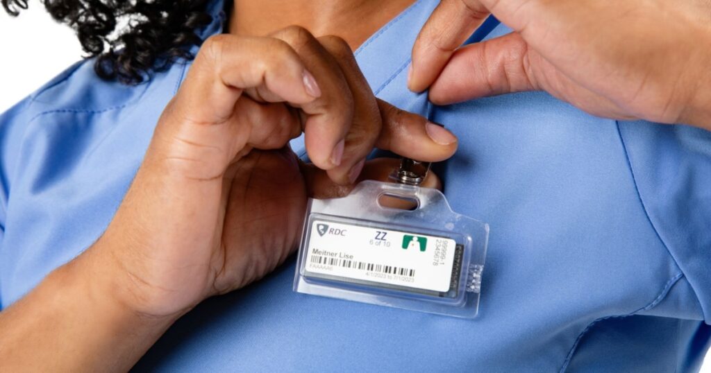 A surgeon clips an OSL badge to her scrubs at the start of a shift.