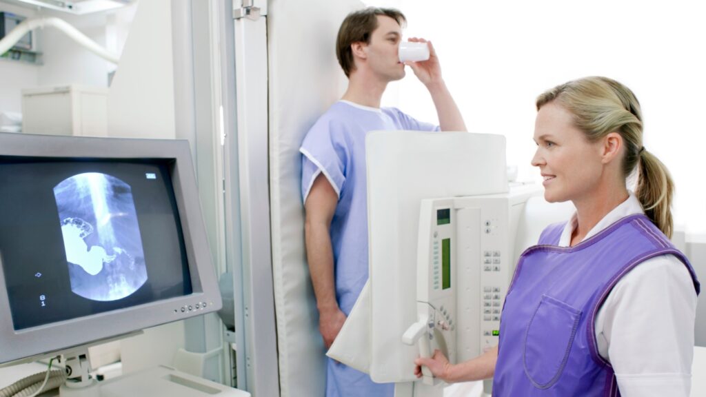 A dental assistant wearing a lead apron takes a client's X-rays during an appointment.