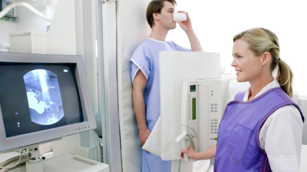 A healthcare worker wears a lead apron while operating imaging equipment.