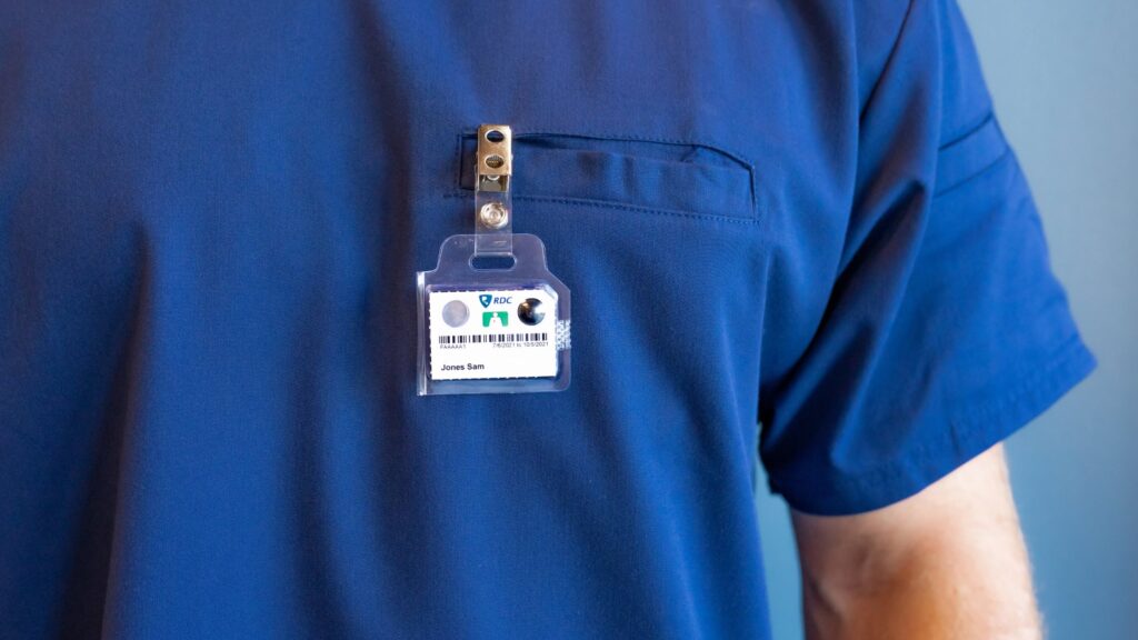 An employee in blue scrubs wears a TLD badge.