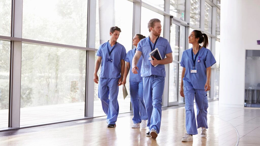 A group of healthcare professionals walk through a hospital outside of an area requiring personal radiation dosimeters.