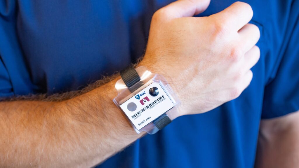 An employee wears a TLD wrist badge for dosimetry monitoring during imaging therapy.