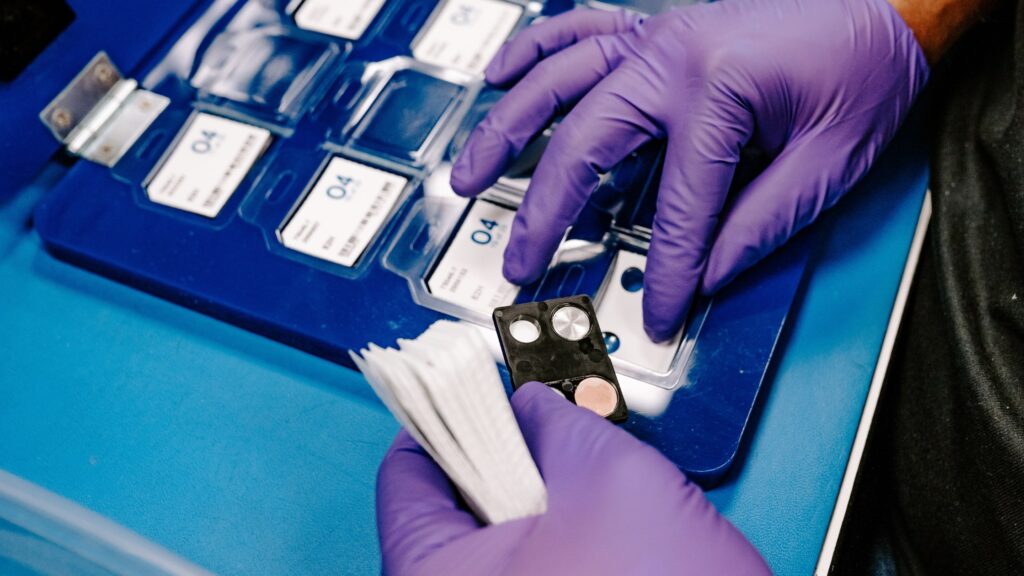 An employee at Radiation Detection Company builds badges using TLD elements.