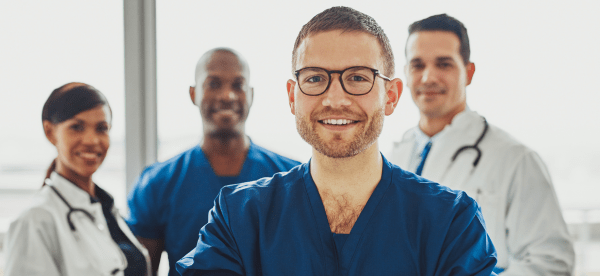 A happy doctor stands in front of a group of smiling medical professionals.