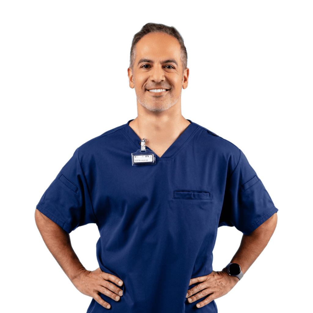 A dental employee wearing dark blue scrubs with his hands on his hips.