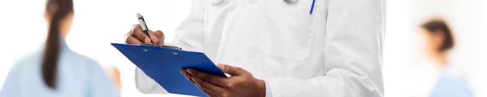 A doctor checks off a clipboard while nurses tend to patients in the background.