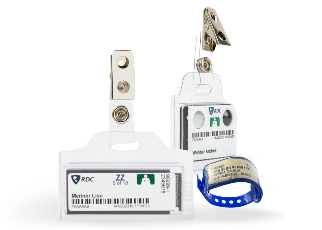 Two electronic badges with clips and an RFID wristband are displayed. The badges feature identification details, and the blue wristband is illuminated.