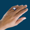 Close-up of a person’s hand wearing a sleek and modern TLD ring on a dark blue background