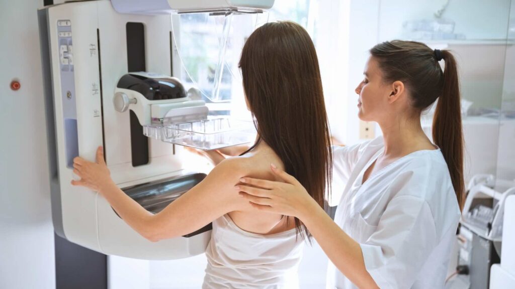 A technologist assists a patient during a mammogram.