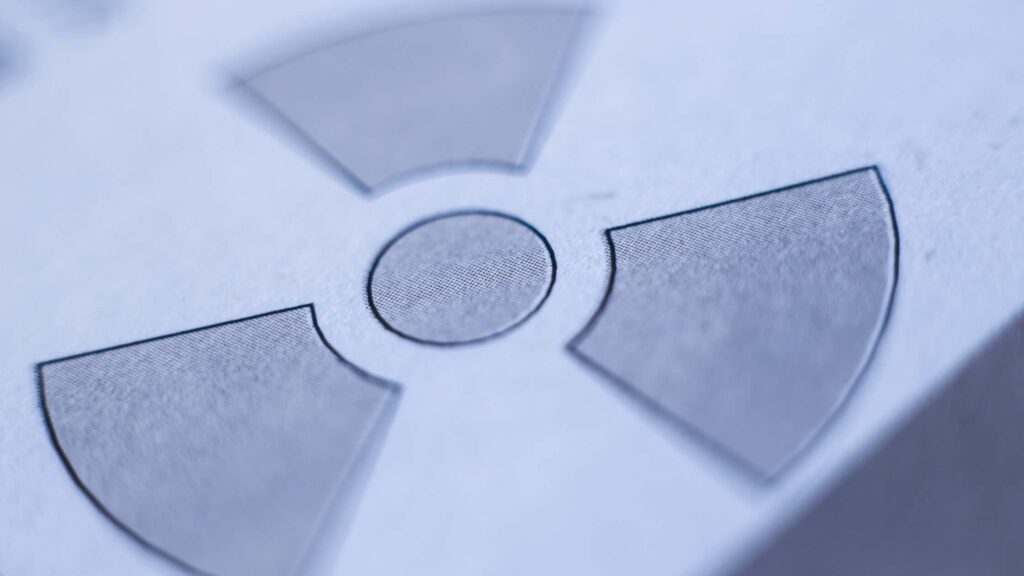 A radiation trefoil printed on paper and partially blurred, representing the blind spots in rereading OSL dosimeters.