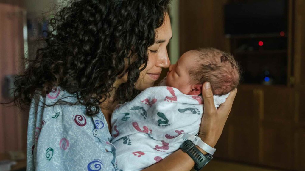 A new mom snuggles her newborn shortly after giving birth.