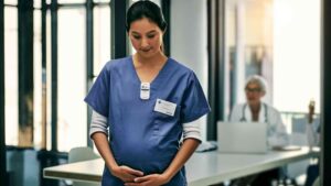 Pregnant healthcare worker wearing NetDose in scrubs.