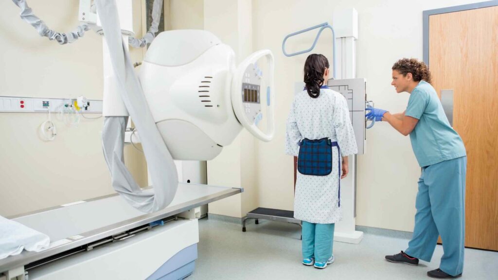 A radiologic technologist aligns equipment before an X-ray.