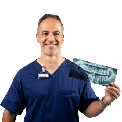 A dentist smiling and holding an X-ray while wearing a dosimeter badge.