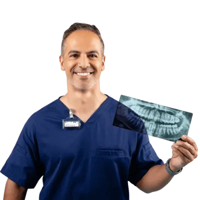 A dentist smiling and holding an X-ray while wearing a dosimeter badge.